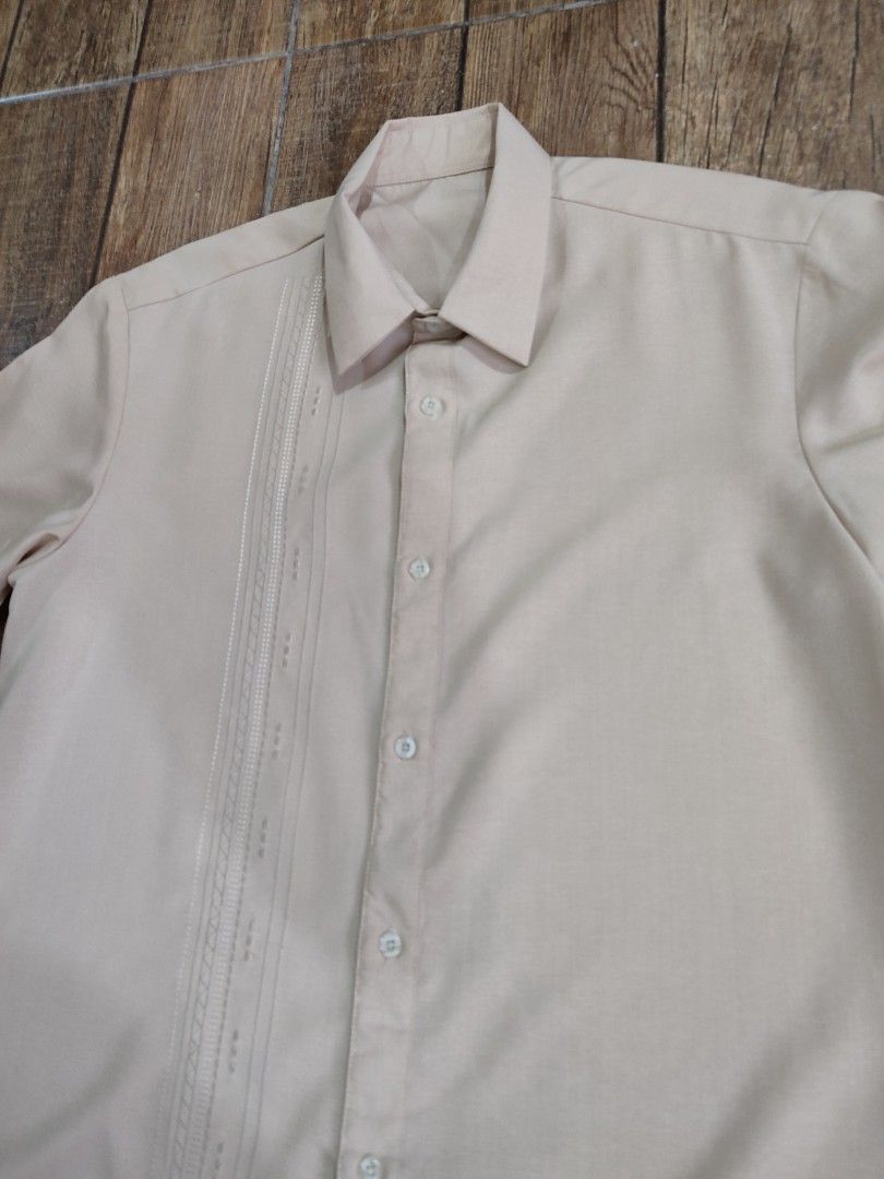 Beige Short Sleeve Shirt (Category: Shirts) located in Dasmarinas. Submitted by sbtt_ (Listing ID 1421639559, Image 3). Description: - Beige short sleeve shirt - Classic collar and button-down closure - Decorative pleats on left chest - Smooth, possibly synthetic fabric - Suitable for casual and semi-formal occasions.