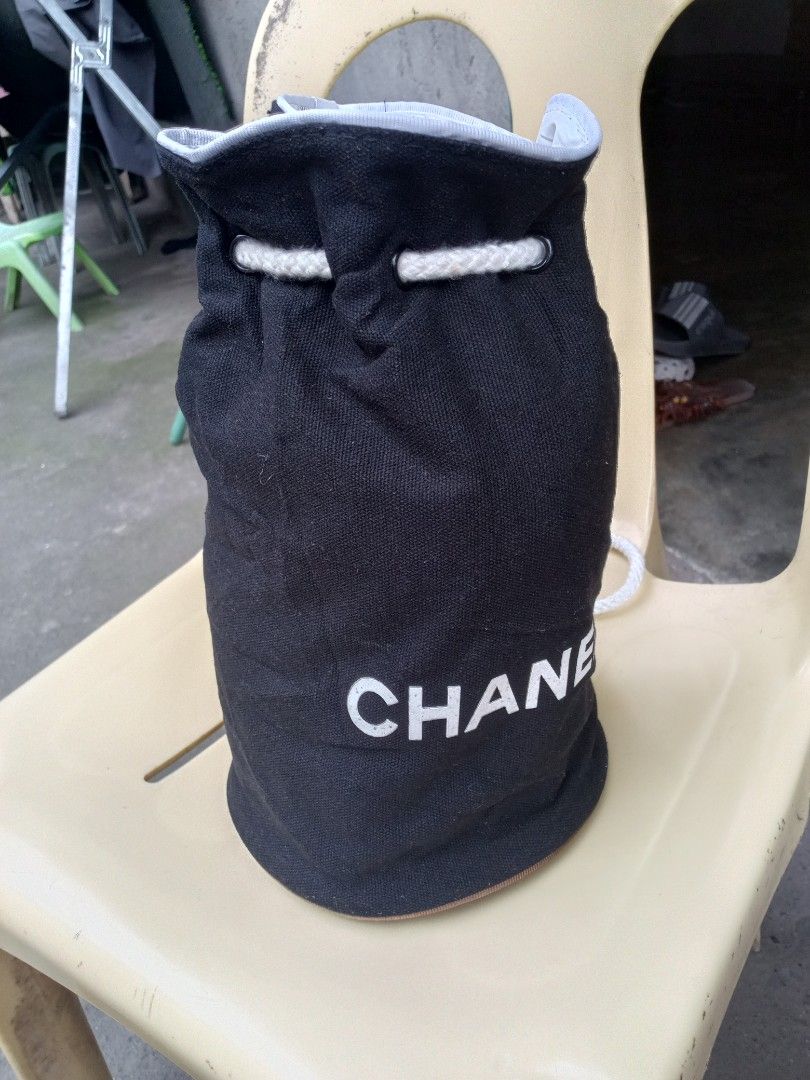 Chanel Bucket Bag (Category: Luxury Bags & Wallets) located in Polomolok. Submitted by delosreyesshyn81134 (Listing ID 1421761191, Image 2). Description: - Black bucket bag - White "CHANEL" logo - Drawstring closure with white rope - Chanel logo patterned lining - Brown trim at the bottom.