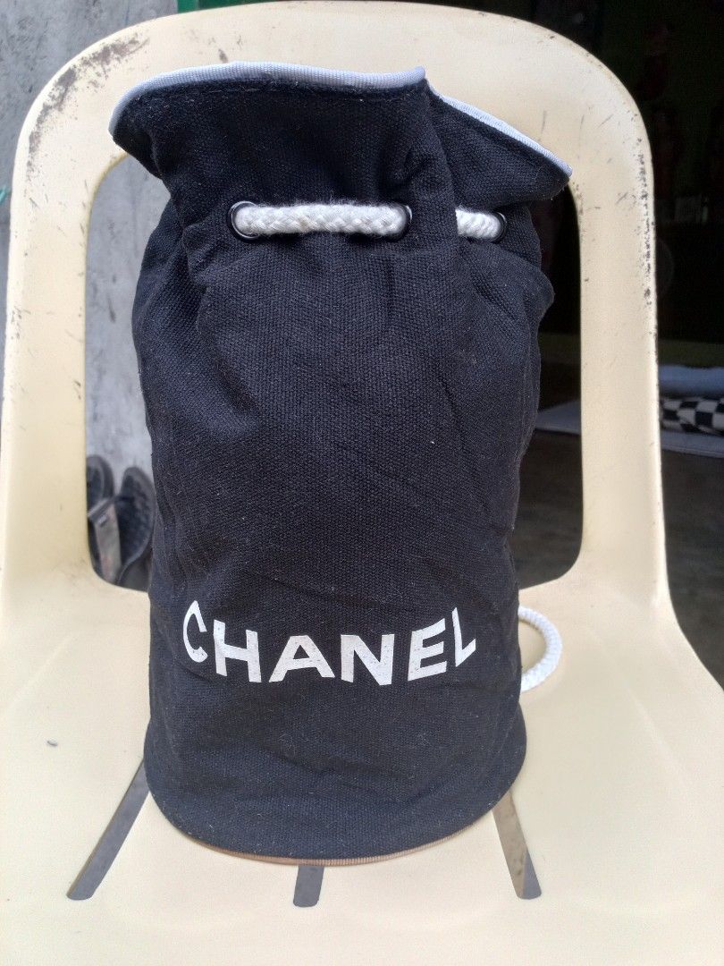 Chanel Bucket Bag (Category: Luxury Bags & Wallets) located in Polomolok. Submitted by delosreyesshyn81134 (Listing ID 1421761191, Image 1). Description: - Black bucket bag - White "CHANEL" logo - Drawstring closure with white rope - Chanel logo patterned lining - Brown trim at the bottom.