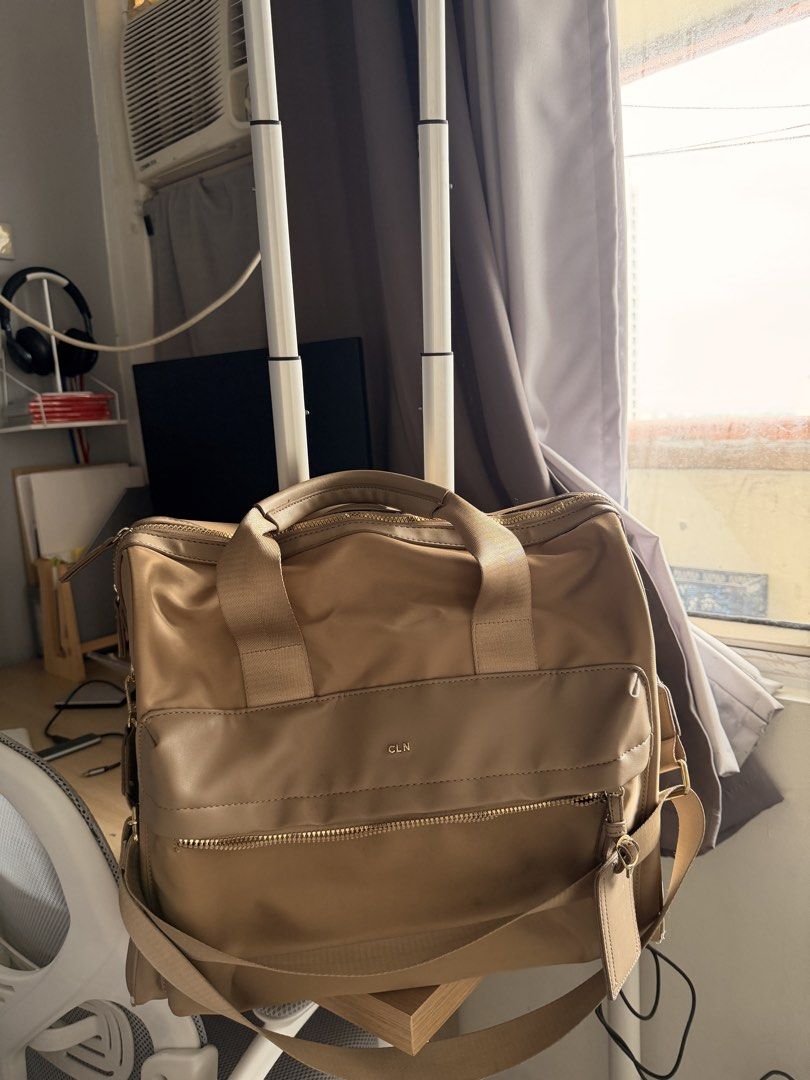 CLN Rolling Bag (Category: Luxury Bags & Wallets) located in Manila. Submitted by ellede32655 (Listing ID 1421653157, Image 2). Description: - CLN tan rolling bag - Top handle and shoulder strap - Wheels for easy transport - Multiple zippered compartments - Includes luggage tag - Shows wear and tear on corners and seams.