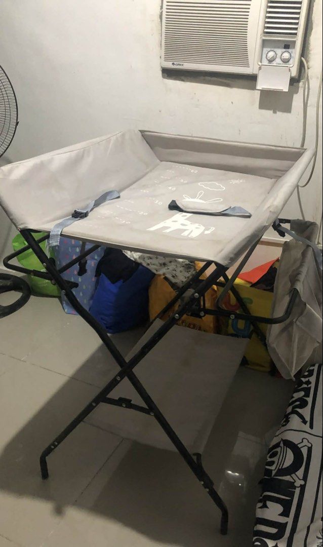 Foldable Baby Changing Table (Category: Changing Mats & Accessories) located in Manila. Submitted by mkydrandom (Listing ID 1421778770, Image 3). Description: - Foldable baby changing table - Gray changing surface with safety strap - Includes storage basket and lower shelf - Space-saving design -no wheels -with visible stains - Dimensions available in images.