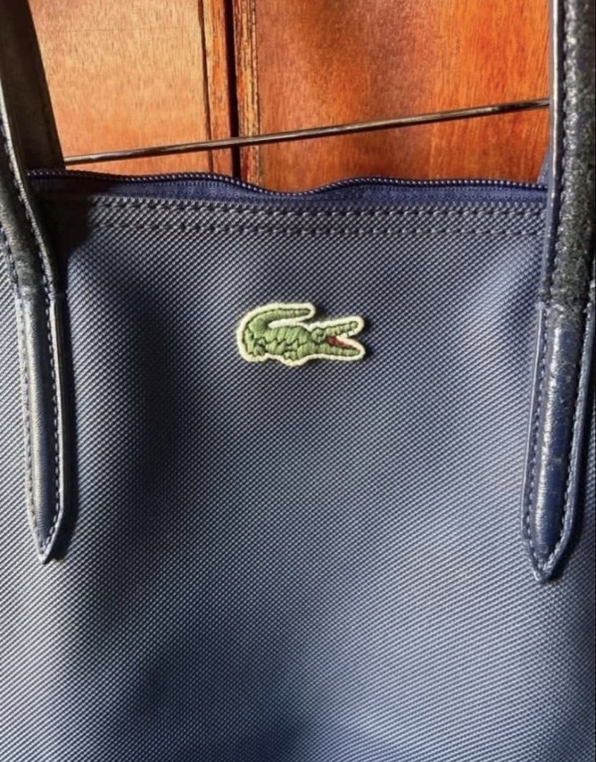 Lacoste Navy Blue Tote Bag (Category: Tote Bags) located in Taguig. Submitted by stuffitlikeitshot (Listing ID 1421704762, Image 2). Description: - Navy blue Lacoste tote bag - Zippered main compartment - Interior pocket - Lacoste logo on front - Lacoste logo on zipper pull - Lacoste logo printed interior lining - see last pic for FLAWS.