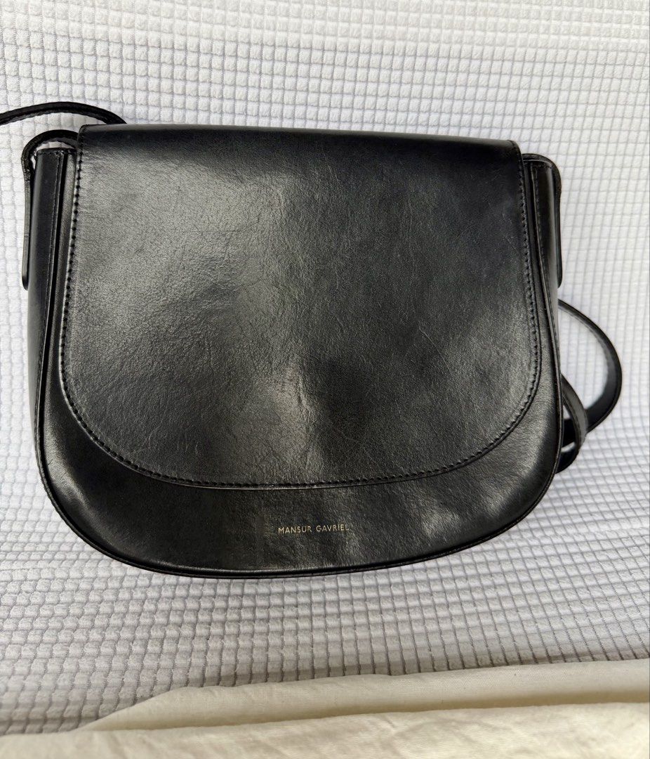 Mansur Gavriel Black Leather Crossbody Bag (Category: Luxury Bags & Wallets) located in Manila. Submitted by mr.arnie (Listing ID 1421748057, Image 1). Description: Black leather crossbody bag from Mansur Gavriel. Features a flap closure and an adjustable shoulder strap. Includes a dust bag. The interior has a slip pocket. Made in Italy. The bag has the Mansur Gavriel logo embossed on the front..