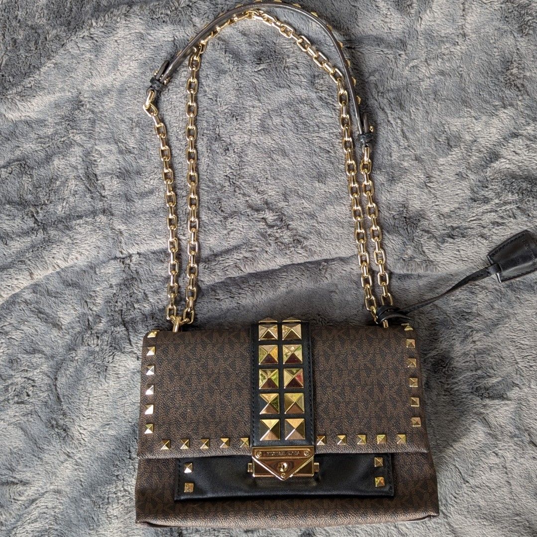 Michael Kors Studded Shoulder Bag (Category: Luxury Bags & Wallets) located in Manila. Submitted by eladp (Listing ID 1421726865, Image 1). Description: - Michael Kors Cece shoulder bag -preloved - Brown monogram pattern - Gold-tone hardware - Chain strap - Adorned with gold studs - Black leather flap - Zippered interior pocket - Brown fabric lining - Magnetic closure ❌No to low ballers.