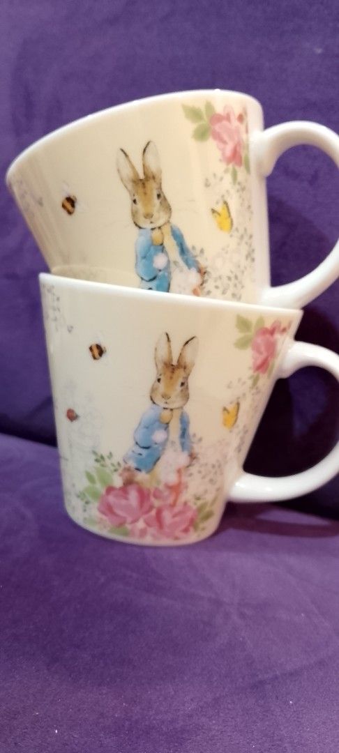 Peter Rabbit Mugs (Category: Coffee & Tea Tableware) located in Cabanatuan. Submitted by miss.maia (Listing ID 1421757958, Image 1). Description: - Set of two Peter Rabbit mugs - Features Peter Rabbit character design - Adorned with floral and insect details - Unique mug shape - Comfortable handle - Peter Rabbit logo on the bottom Couple mugs for 999 - Perfect for hot beverages.