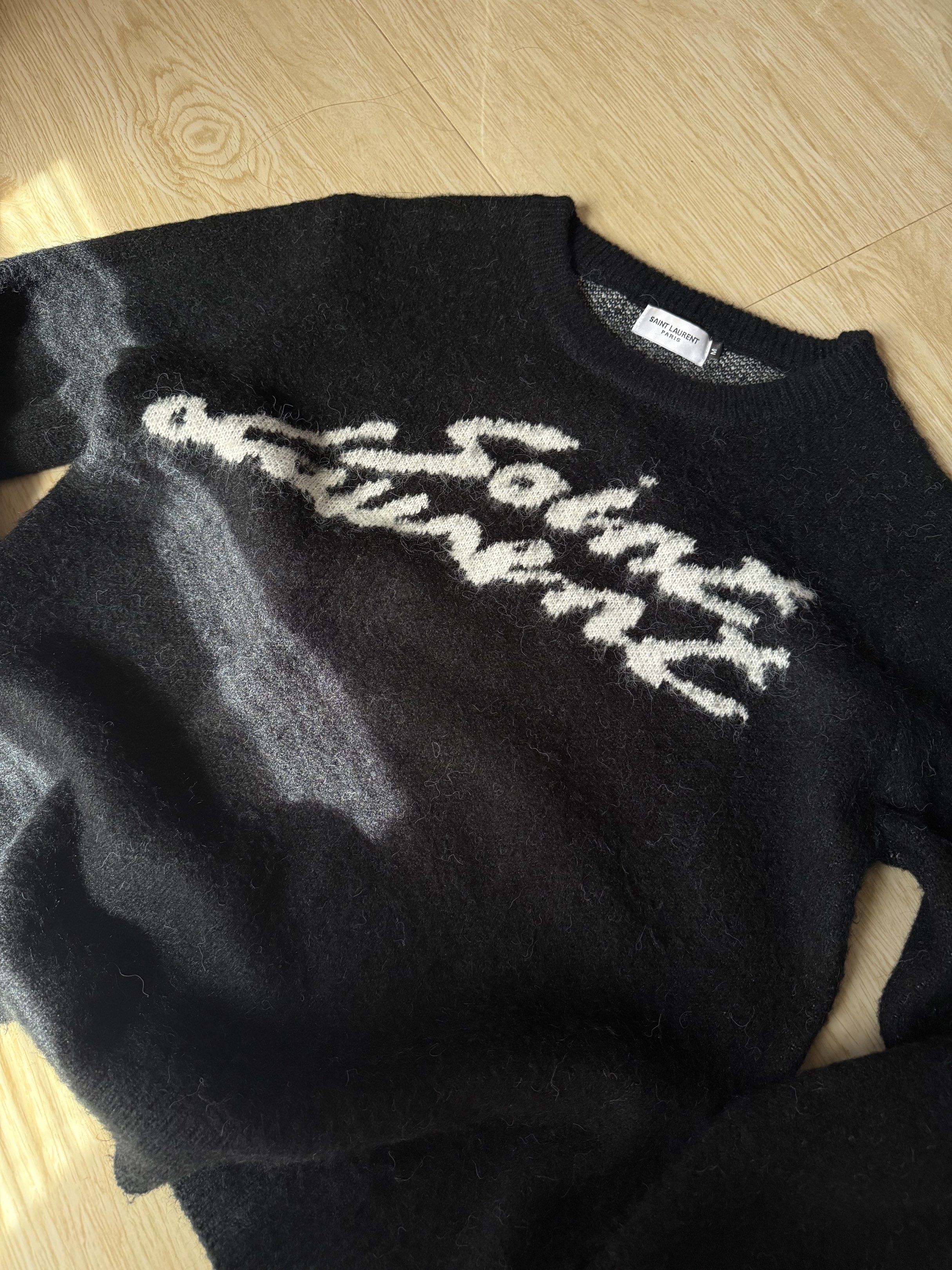 Saint Laurent Paris Sweater (Category: Luxury Apparel) located in Meycauayan. Submitted by jhonedrickso12 (Listing ID 1421633173, Image 2). Description: - Saint Laurent Paris sweater - Black with white lettering - Size: M - Crew neck - Long sleeves - Textured fabric.
