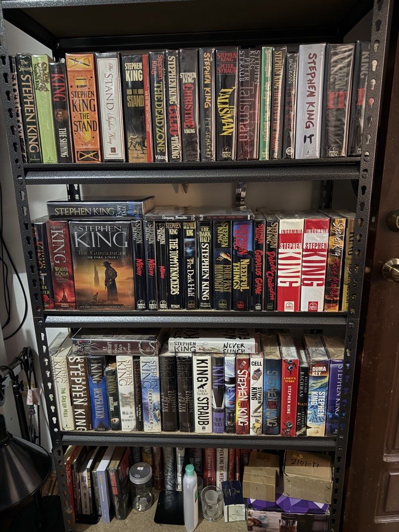 Stephen King Book Collection (Category: Storybooks) located in Quezon City. Submitted by IMTRANSPORT (Listing ID 1421064261, Image 3). Description: - Stephen King book collection. - Titles include: "The Stand", "The Shining", "The Dead Zone", "Christine", "Pet Sematary", "Talisman", "Needful Things", "Gerald's Game", "The Tommyknockers", "Cell", "It", and more. - Books are arranged on a metal shelf. - Features a mix of editions, including some ol