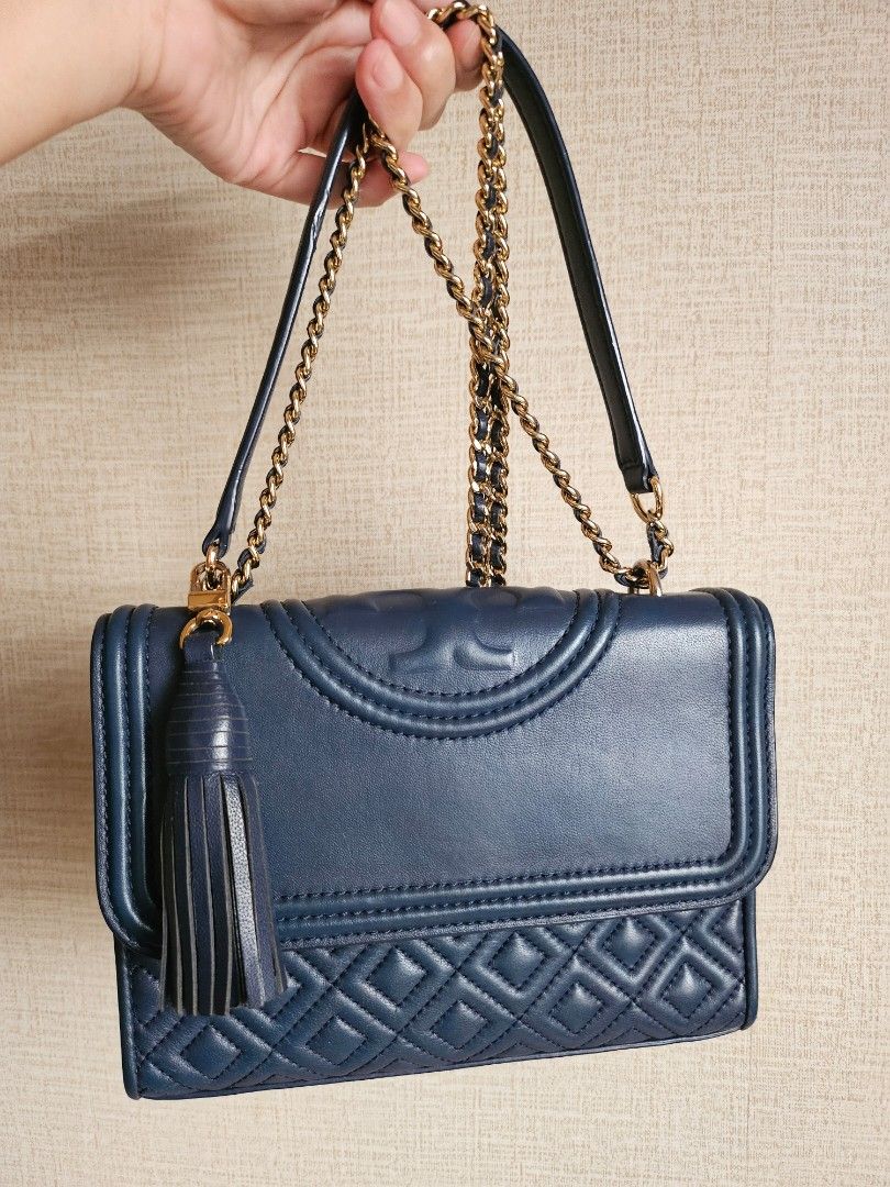 Tory Burch Fleming (small) (Category: Luxury Bags & Wallets) located in Malabon City. Submitted by dadasoliveria (Listing ID 1421661769, Image 1). Description: - Tory Burch Fleming (small) - Color: Navy blue 📍dimensions Lenght: 6" = 15cm Width: 8" = 21cm Thickness: 1.5" - 2" - Quilted design - Gold-tone chain strap - Tassel detail - Flap closure with magnetic snap - Interior zippered pocket - Tory Burch branded tag - Includes dust bag *** can fi