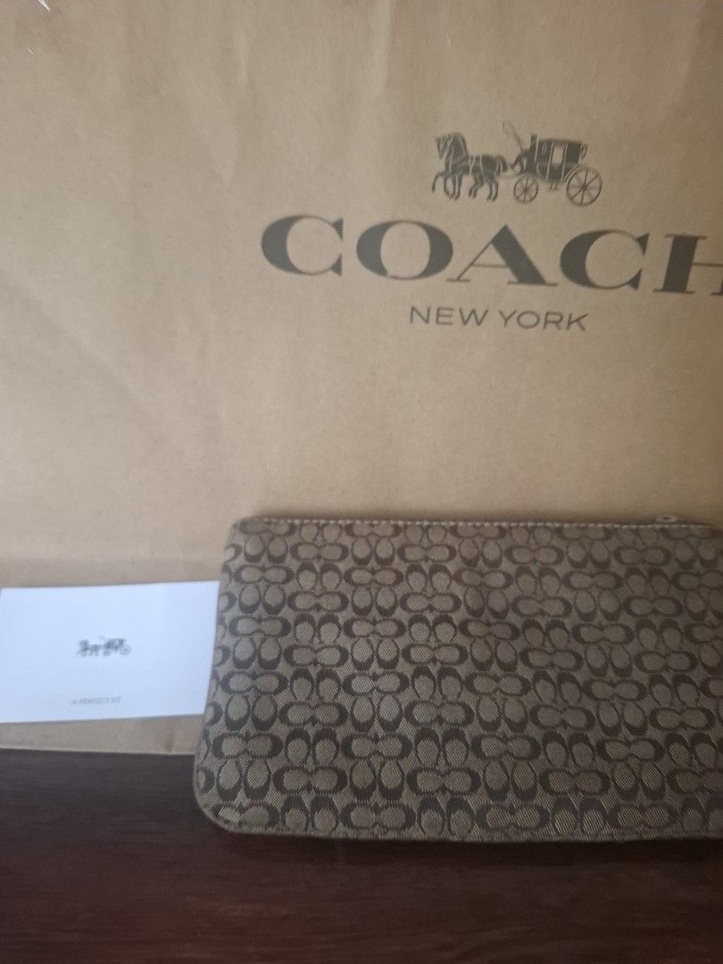 Coach Signature Clutch (Category: Luxury Bags & Wallets) located in Quezon City. Submitted by cncarousel (Listing ID 1421843327, Image 3). Description: - Authentic Coach clutch - Signature print - Buckle closure - Wrist strap - Single compartment - Includes Coach paper bag and care card - Brown exterior with tan leather accents - Coach logo visible.