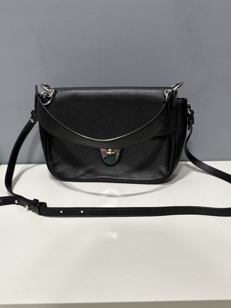 Coccinelle Black Leather Shoulder Bag (Category: Luxury Bags & Wallets) located in Paranaque City. Submitted by caityprecky (Listing ID 1421799964, Image 2). Description: Black leather shoulder bag by Coccinelle. Features a flap closure with a silver-tone clasp. Includes a shoulder strap and a back pocket. The interior has a zippered pocket and a small logo tag that says "Authentic Italian Leather"..