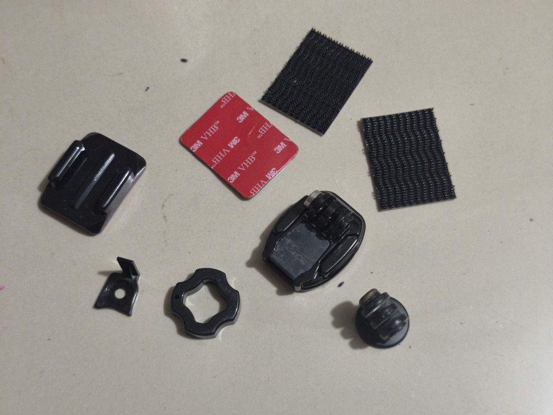 GoPro Mounts and Accessories (Category: Cameras) located in Taguig. Submitted by juliestjuly (Listing ID 1421813167, Image 1). Description: Includes various GoPro mounts and accessories. Features a black plastic mount with a 'REMOVE' label, adhesive pads, and other mounting components. Perfect for attaching your GoPro camera to different surfaces. Includes a variety of pieces for versatile mounting options..