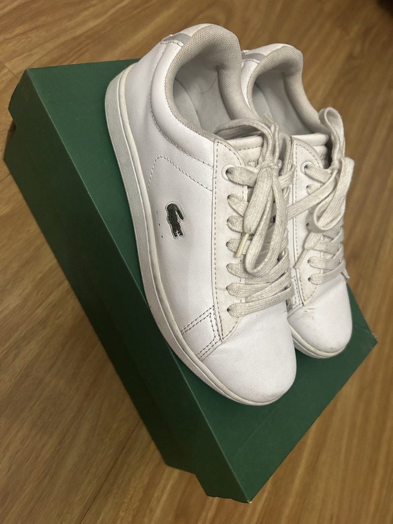 Lacoste White Sneakers (Category: Sneakers) located in Marikina City. Submitted by fm.ty (Listing ID 1421851555, Image 2). Description: White Lacoste sneakers with the iconic crocodile logo. Features a classic lace-up design. Includes the original green Lacoste box. The sneakers have a white upper and a white sole. The Lacoste logo is visible on the side and the heel of the shoes. Original Price: Php 6,500.