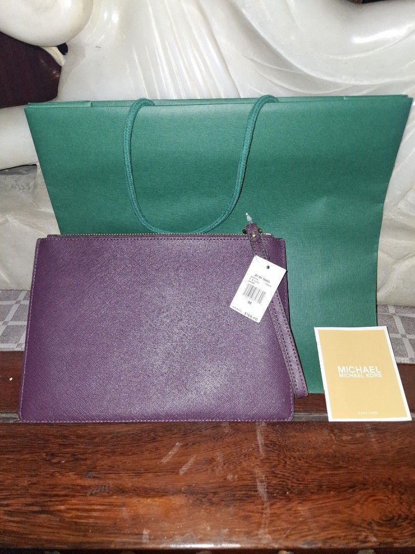 Michael Kors Clutch (Category: Clutches) located in Quezon City. Submitted by cncarousel (Listing ID 1421891743, Image 2). Description: - Michael Kors clutch in a beautiful purple color. - Features a unique patterned design. - Comes with a matching wrist strap. - Includes a Michael Kors tag and care card. - Comes with a green shopping bag. - Perfect for carrying your essentials in style..
