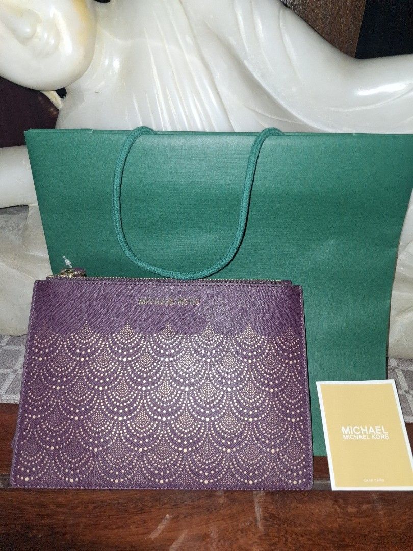 Michael Kors Clutch (Category: Clutches) located in Quezon City. Submitted by cncarousel (Listing ID 1421891743, Image 1). Description: - Michael Kors clutch in a beautiful purple color. - Features a unique patterned design. - Comes with a matching wrist strap. - Includes a Michael Kors tag and care card. - Comes with a green shopping bag. - Perfect for carrying your essentials in style..