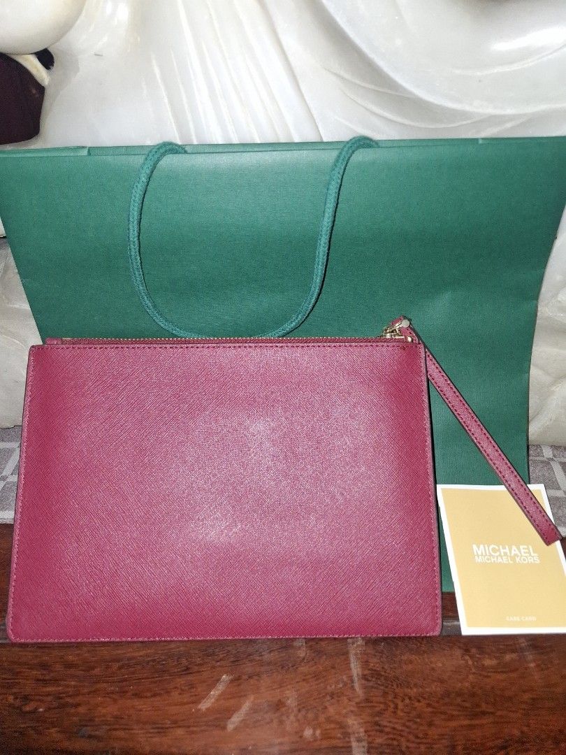 Michael Korrs Jet Set Travel Clutch (Category: Luxury Bags & Wallets) located in Quezon City. Submitted by cncarousel (Listing ID 1421891893, Image 2). Description: Authentic Michael Kors Jet Set Travel clutch. Features a burgundy color with a decorative pattern on the front. Includes a wrist strap and a zipper closure. Comes with a Michael Kors tag and a green shopping bag. The tag indicates the color is 'Mulberry'..
