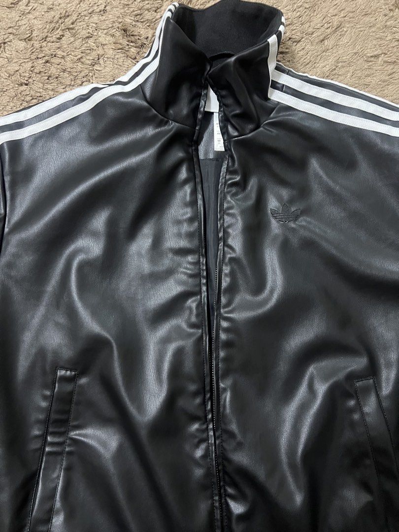 Adidas Leather Jacket with Stripes (Category: Coats, Jackets and Outerwear) located in Manila. Submitted by cluttercrushers (Listing ID 1422009596, Image 3). Description: - Adidas jacket features a sleek black leather design with the iconic three stripes on the sleeves. - It has a full zip closure, a stand-up collar, and the Adidas logo on the chest. - The jacket includes two front pockets and ribbed cuffs and hem for a comfortable fit. The tags 