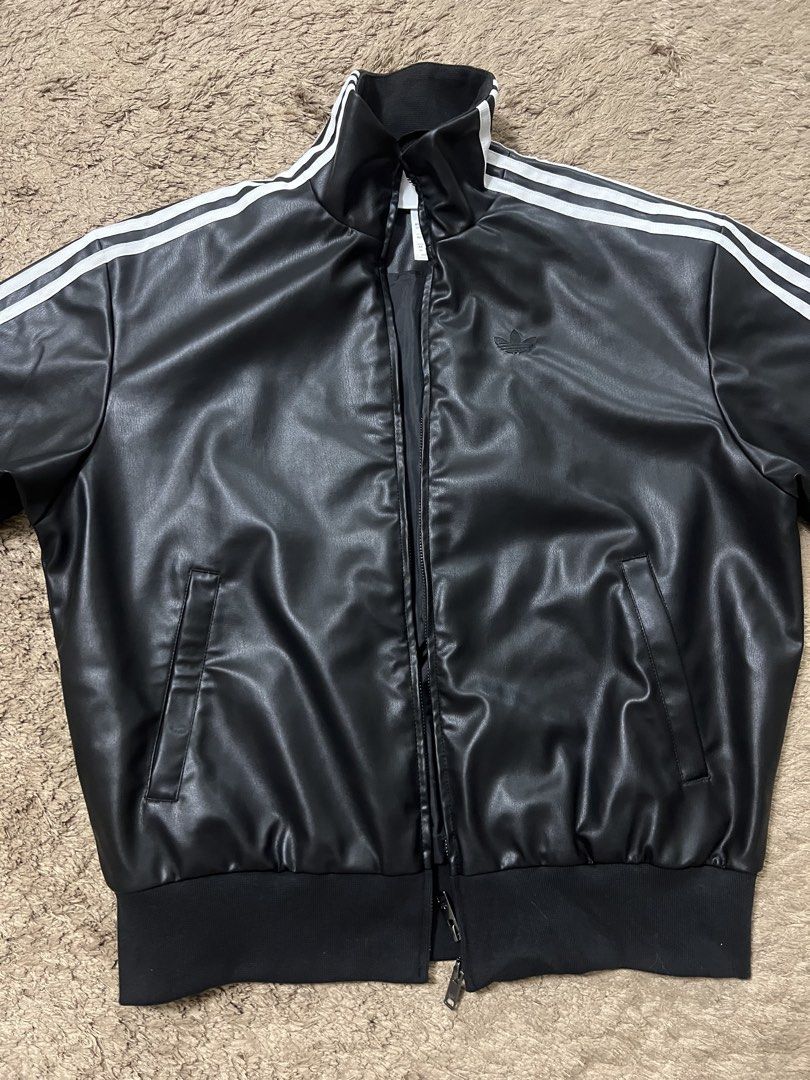 Adidas Leather Jacket with Stripes (Category: Coats, Jackets and Outerwear) located in Manila. Submitted by cluttercrushers (Listing ID 1422009596, Image 1). Description: - Adidas jacket features a sleek black leather design with the iconic three stripes on the sleeves. - It has a full zip closure, a stand-up collar, and the Adidas logo on the chest. - The jacket includes two front pockets and ribbed cuffs and hem for a comfortable fit. The tags 