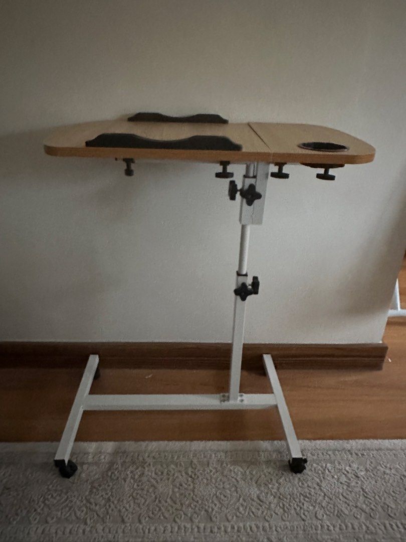 Adjustable Height Bedside Table (Category: Tables & Sets) located in Shah Alam. Submitted by rarebird.b4a092 (Listing ID 1422017871, Image 2). Description: - Adjustable height & foldable design - Made of pro-wooden material - Size: (40+20)*40 - Includes a cup holder - Dedicated section for laptop or tablet - Mounted on wheels for easy mobility.