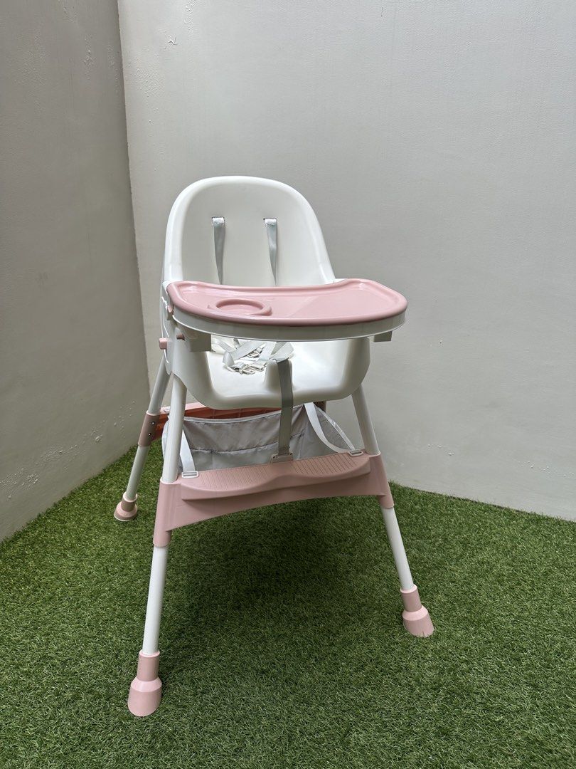 Baby High Chair with Tray (Category: Baby High Chairs) located in Paranaque City. Submitted by every_thingph (Listing ID 1421954324, Image 2). Description: - White and pink high chair - Designed for babies and toddlers - Removable tray for easy cleaning - Includes a safety harness for security - Convenient storage basket - Easy-to-clean plastic seat - Comfortable footrest - Pink accents on legs.