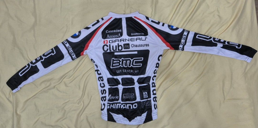 BMC Cycling Jersey and Bib Tights Set - Medium (Category: Babies & Kids Fashion) located in Manila. Submitted by bajoyskie (Listing ID 1422051840, Image 2). Description: Cycling kit includes a long-sleeved jersey and bib tights. The jersey features the BMC and Shimano logos, with a half-zip closure. The bib tights have a padded seat. Both pieces are black and white with BMC branding. The size tag indicates a Medium size. The jersey is made of 100