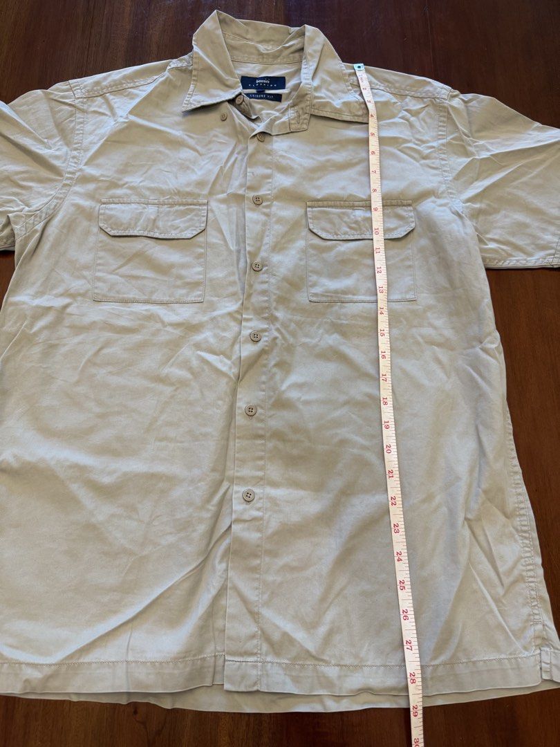Bossini Leisure Fit Shirt - Medium (Category: Shirts) located in Mandaue City. Submitted by marginiz (Listing ID 1421953577, Image 2). Description: Bossini Leisure Fit shirt in size Medium. Features a button-down closure, two chest pockets, and short sleeves. The shirt is a neutral beige color. Measurements are approximately 29 inches in length and 20 inches across the chest. Made of a comfortable fabric suitable for casual wear..