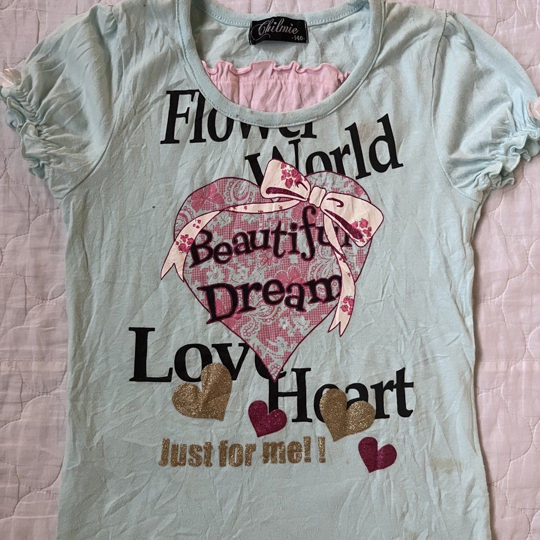 Chilmie Flower World Graphic Baby Tee (Category: Shirts) located in Manila. Submitted by meeeeeraaa (Listing ID 1422020160, Image 2). Description: Chilmie t-shirt with a light blue base, 'Flower World' graphic, ruffled sleeves, and pink inner layer. Features a heart design with glitter. Note: Visible stains on the front and sides. FREE FOR MINERS.