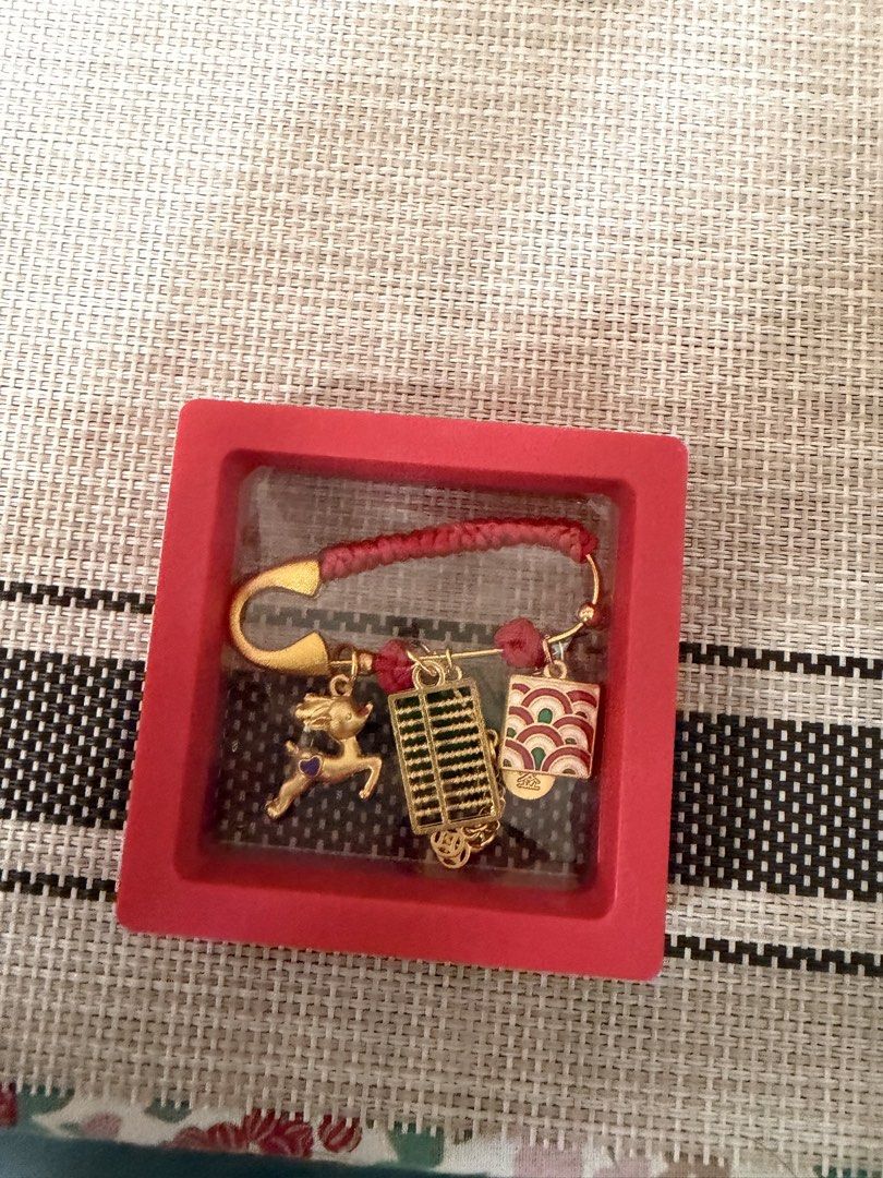 Lucky Charm Keychain with Decorative Charms (Category: Charms) located in Manila. Submitted by pepperang318 (Listing ID 1421960027, Image 2). Description: - Features a red cord and gold safety pin. - Adorned with decorative charms including a deer and cart. - Includes other auspicious symbols. - Presented in a red display box. - Colorful and uniquely shaped accessory..