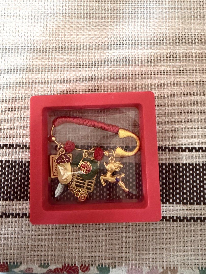 Lucky Charm Keychain with Decorative Charms (Category: Charms) located in Manila. Submitted by pepperang318 (Listing ID 1421960027, Image 1). Description: - Features a red cord and gold safety pin. - Adorned with decorative charms including a deer and cart. - Includes other auspicious symbols. - Presented in a red display box. - Colorful and uniquely shaped accessory..