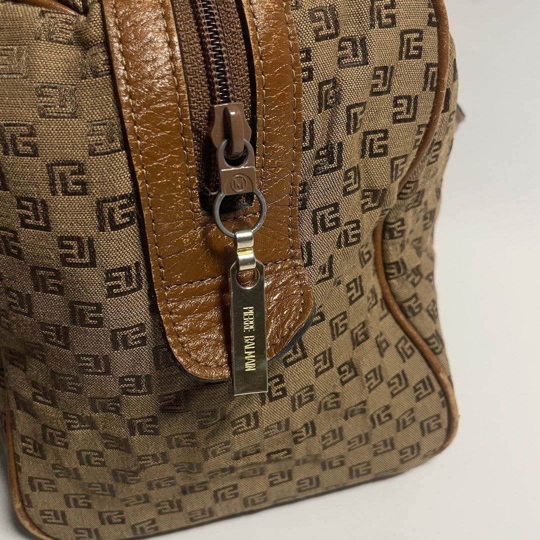 Pierre Balmain Brown Handbag (Category: Luxury Bags & Wallets) located in Cabiao. Submitted by mark_galang (Listing ID 1421952989, Image 3). Description: - Pierre Balmain handbag - Brown color with repeating logo pattern - Brown leather handles and trim - Zipper closure with Pierre Balmain tag - Metal feet on the bottom - Interior features matching logo pattern - Interior tag number: 195603.