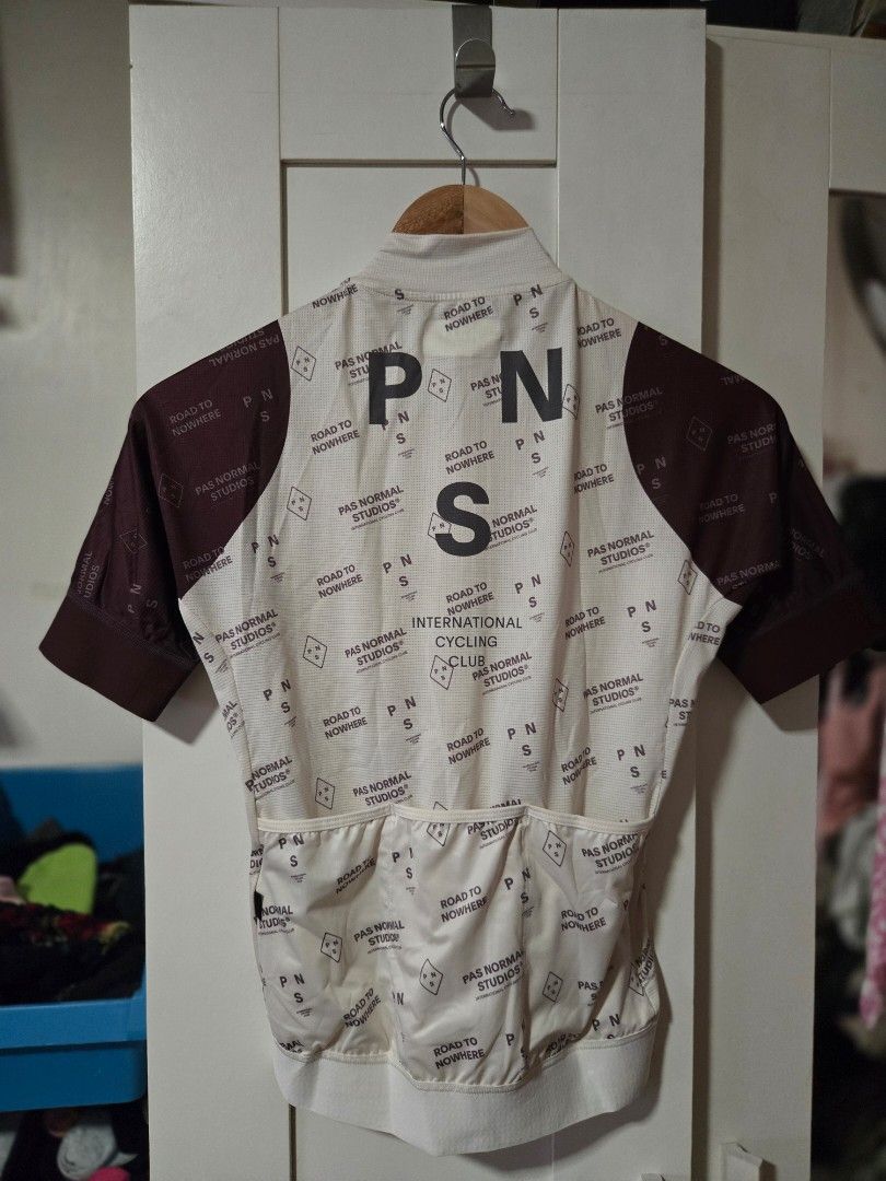 PN International Cyclist Jersey (Category: Activewear) located in Quezon City. Submitted by ddlry (Listing ID 1422004569, Image 2). Description: - Full zip cycling jersey - White base with unique repeating pattern - Brown accents on sleeves - "PNS" logo on the back - Designed for comfortable cycling.