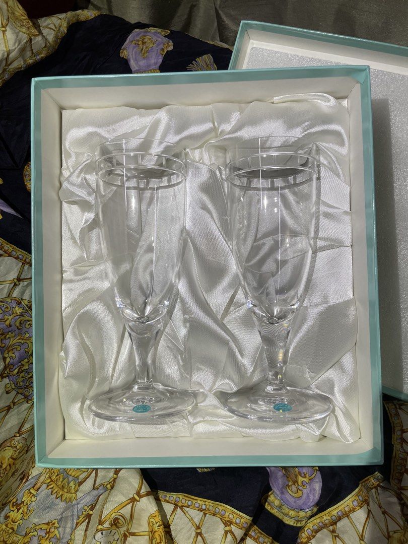 Tiffany & Co. Champagne Flutes (Category: Dinnerware & Cutlery) located in Plaridel. Submitted by collectorscamp (Listing ID 1422047048, Image 2). Description: - Set of two Tiffany & Co. champagne flutes - Elegant clear glass design with silver rims - Features the iconic Tiffany & Co. logo on the base - Comes in the original Tiffany & Co. box - Box includes a luxurious satin lining - Made in Japan.