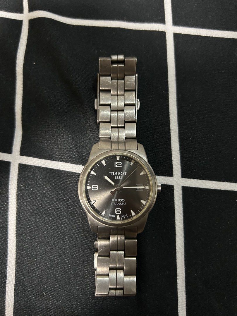 Tissot PR 100 Titanium Watch (Category: Luxury Watches) located in Quezon City. Submitted by hubertpasiona (Listing ID 1422046420, Image 1). Description: - Tissot PR 100 Titanium watch - Titanium case and bracelet - Dark gray dial with silver-tone hands and markers - Date window at 3 o'clock - Displays Tissot logo and "PR 100 Titanium".