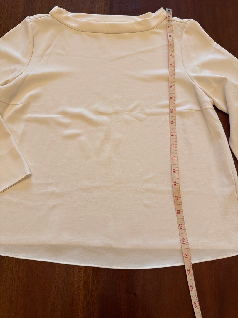 Uniqlo White Blouse - Size M (Category: Blouses) located in Mandaue City. Submitted by marginiz (Listing ID 1421956046, Image 2). Description: White blouse from Uniqlo, size M. Features a boat neck and long sleeves with flared cuffs. The blouse has a straight hemline. The length is approximately 23 inches, and the width is about 16 inches. Made in China..