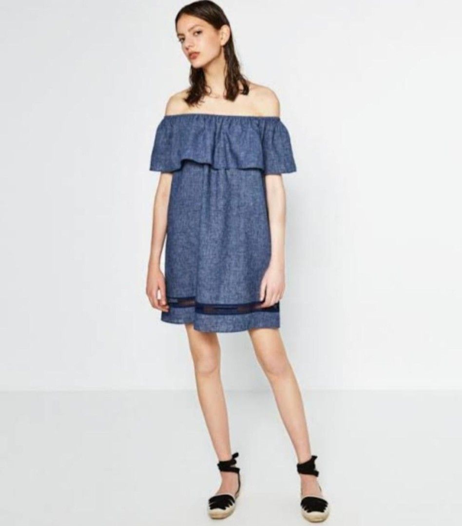 Zara Basic Z1975 Denim Off-Shoulder Dress (Category: Dresses) located in Bulacan. Submitted by bnbig (Listing ID 1422064283, Image 1). Description: Zara Basic denim dress features an off-shoulder design with a ruffled neckline. It has short sleeves and a straight hemline. The dress includes a dark navy mesh detail at the bottom. The size is S. Perfect for a casual day out or a beach trip. Made in Turkey. In very light weight clothing fabric Very 