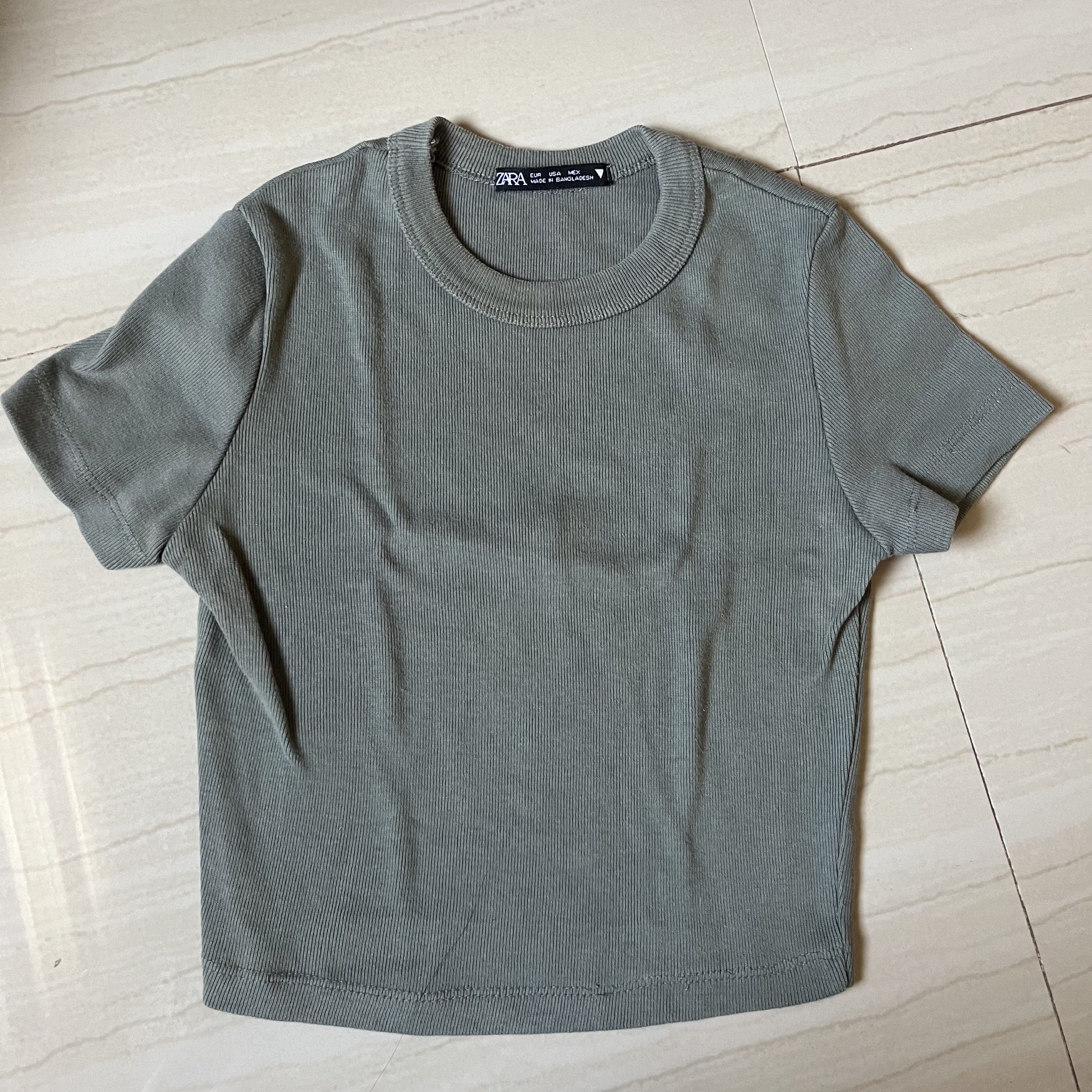 Zara Crop Tops Bundle (Category: Others Tops) located in San Pedro. Submitted by tinybubbless (Listing ID 1421955786, Image 3). Description: Set of Zara crop tops in various colors. Includes a white top with buttons, a brown V-neck top with buttons, a green crew neck top, and a light purple crew neck top. All tops appear to be made of a ribbed material. Perfect for casual wear..