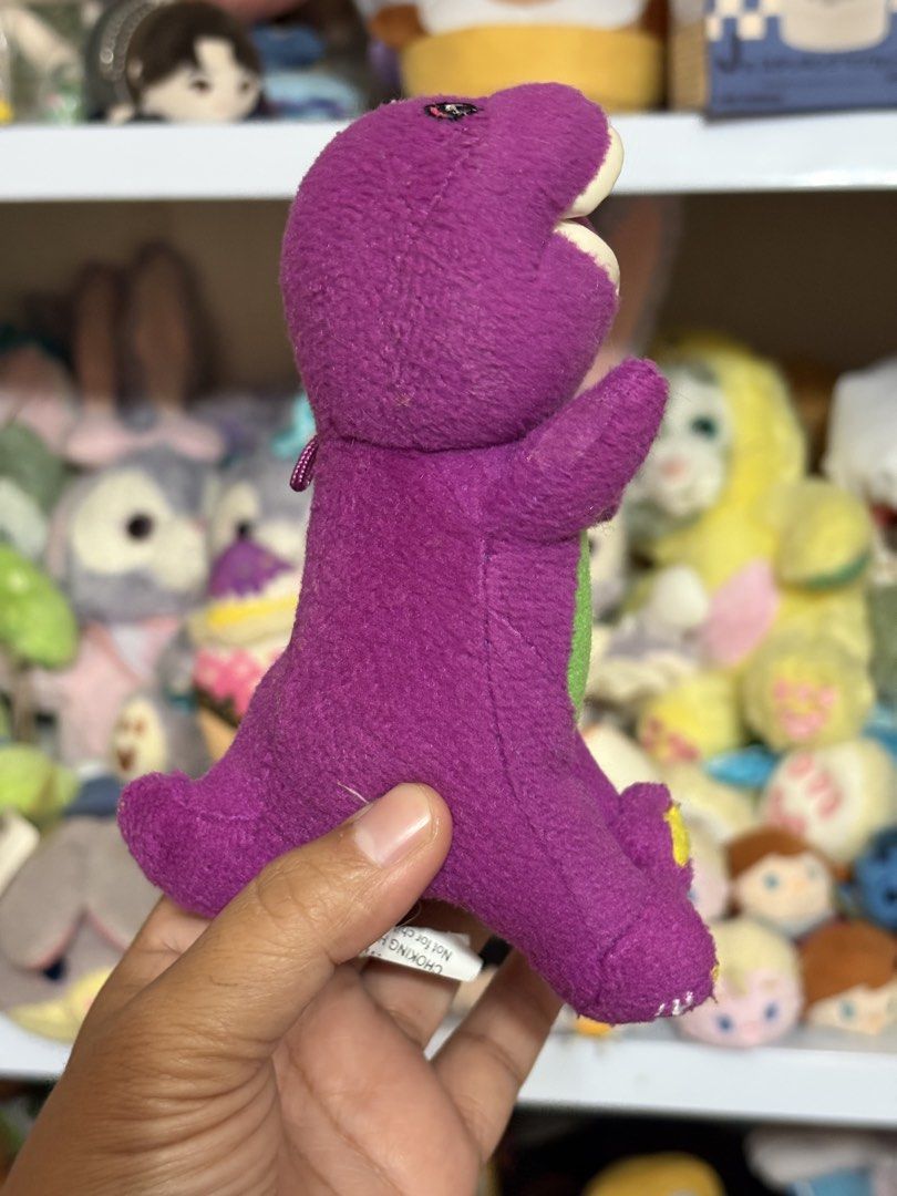 Barney the Dinosaur Plush Charm Keychain (Category: Plushies & Soft Toys) located in Antipolo. Submitted by bhabiegraciefashionlab (Listing ID 1422233046, Image 2). Description: - Classic Barney the Dinosaur plush toy - Features the iconic purple color and green belly - Includes a heart detail - Yellow accents on the feet - "Barney" embroidered on the bottom of the feet - Constructed with all new materials (cotton and polyester stuffing).