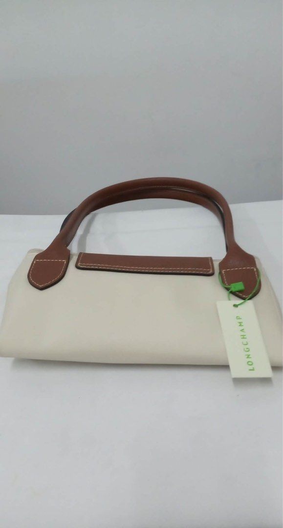 Longchamp Le Pliage Tote Bag in small (Category: Luxury Bags & Wallets) located in Quezon City. Submitted by herluxe_official (Listing ID 1422082579, Image 3). Description: - Authentic Longchamp Le Pliage tote bag - Cream nylon body - Brown leather handles and flap - Gold-tone snap closure - Includes Longchamp tag - Rectangular shape - Spacious interior - Ideal for everyday use.