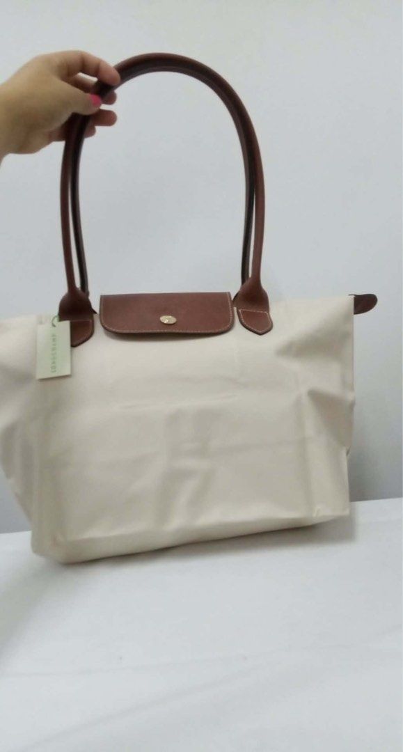 Longchamp Le Pliage Tote Bag in small (Category: Luxury Bags & Wallets) located in Quezon City. Submitted by herluxe_official (Listing ID 1422082579, Image 2). Description: - Authentic Longchamp Le Pliage tote bag - Cream nylon body - Brown leather handles and flap - Gold-tone snap closure - Includes Longchamp tag - Rectangular shape - Spacious interior - Ideal for everyday use.