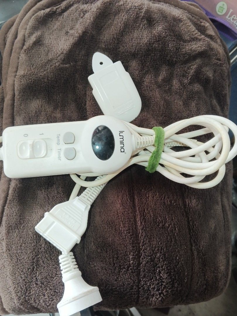 Lumina Electric Heating Pad (Category: Massage Devices) located in Caloocan City. Submitted by surplusandbnewshop (Listing ID 1422232635, Image 2). Description: Lumina electric heating pad features a brown, plush surface. It includes a control unit with temperature and timer settings. The pad has a detachable power cord and a separate control unit holder. The power plug is a standard type..