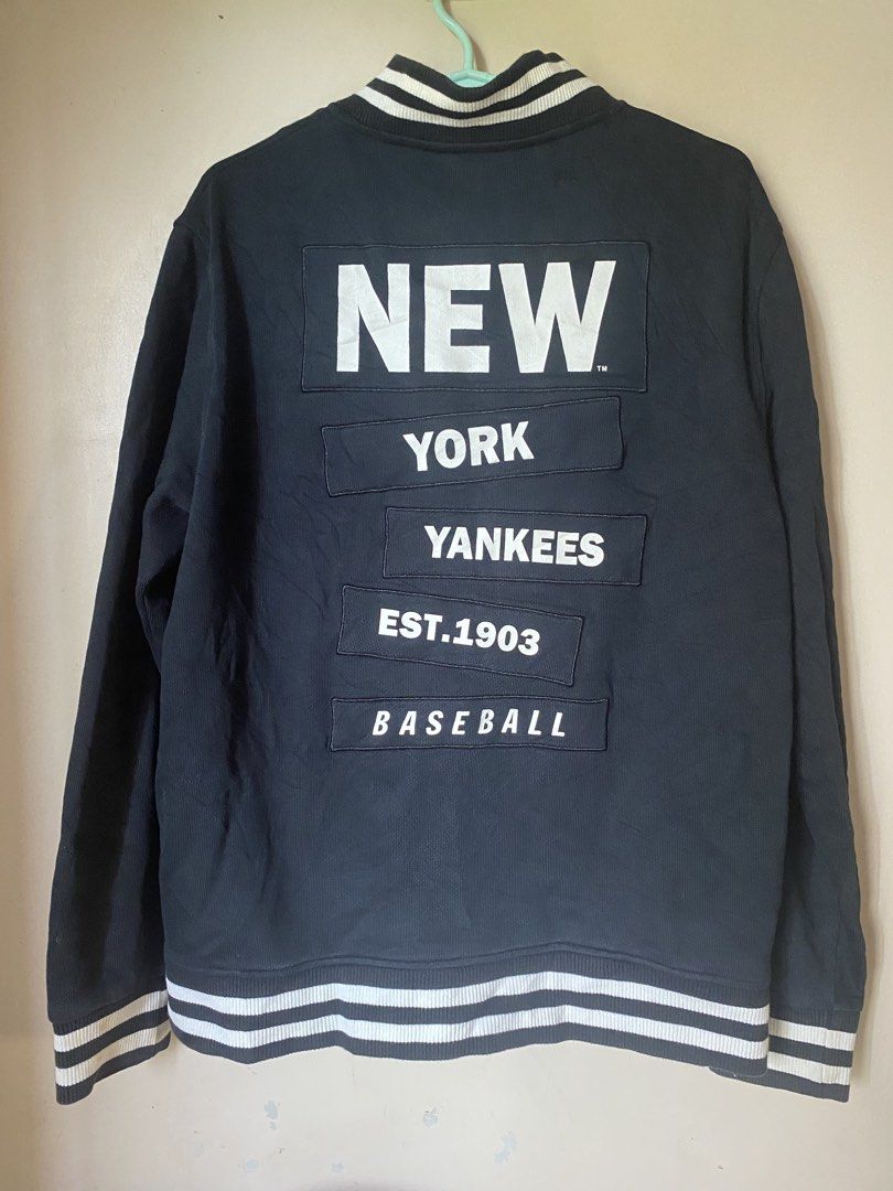 New York Yankees Baseball Jacket (Category: Coats, Jackets and Outerwear) located in Calapan. Submitted by yowstuff (Listing ID 1422150427, Image 2). Description: - Navy blue New York Yankees baseball jacket - Features Yankees logo on the front - "NEW YORK YANKEES EST. 1903 BASEBALL" on the back - Button closures - Striped detailing on collar, cuffs, and hem - Includes tag with Chinese characters.