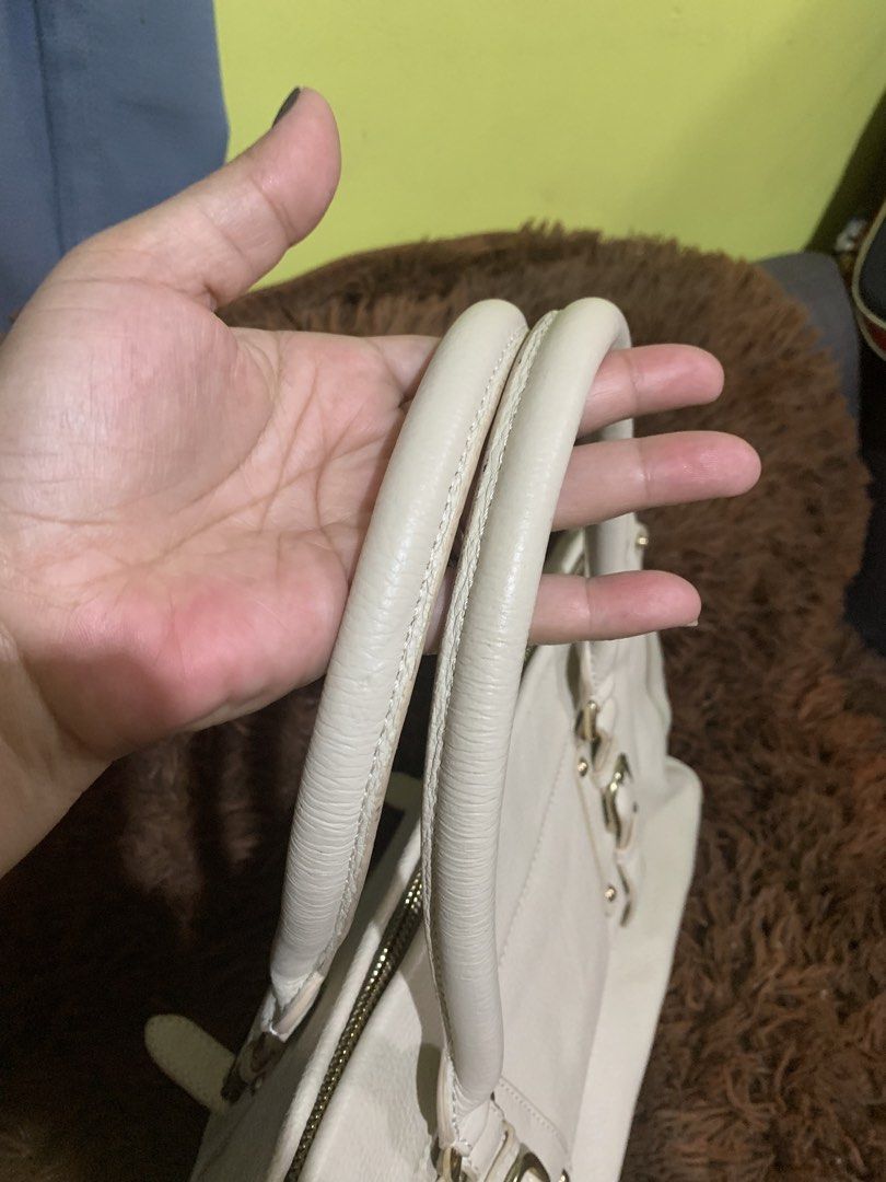 Prada White Leather Handbag (Category: Luxury Bags & Wallets) located in Liloan. Submitted by jinalyns (Listing ID 1422229640, Image 3). Description: Prada handbag in white leather. Features dual top handles, a zip closure, and gold-tone hardware. The interior is lined with brown fabric and includes a Prada logo. The bag has a pebbled leather exterior and a structured shape. Includes a zipper pull with the Prada Milano logo. Lacking letter R.