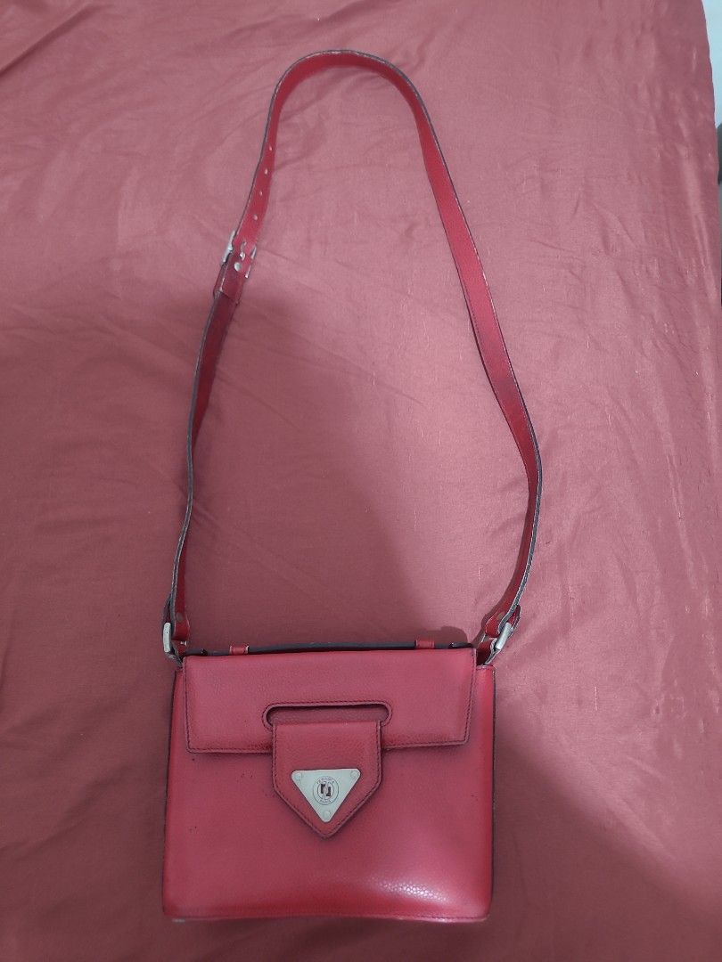 RENOMA Red Shoulder Bag with Triangle Clasp (Category: Luxury Bags & Wallets) located in Orani. Submitted by authentique_collector (Listing ID 1422183405, Image 1). Description: Red shoulder bag features a unique triangle clasp. It has a long strap for comfortable wear. The bag opens to reveal a main compartment with a zipper. The exterior shows a smooth, glossy finish..