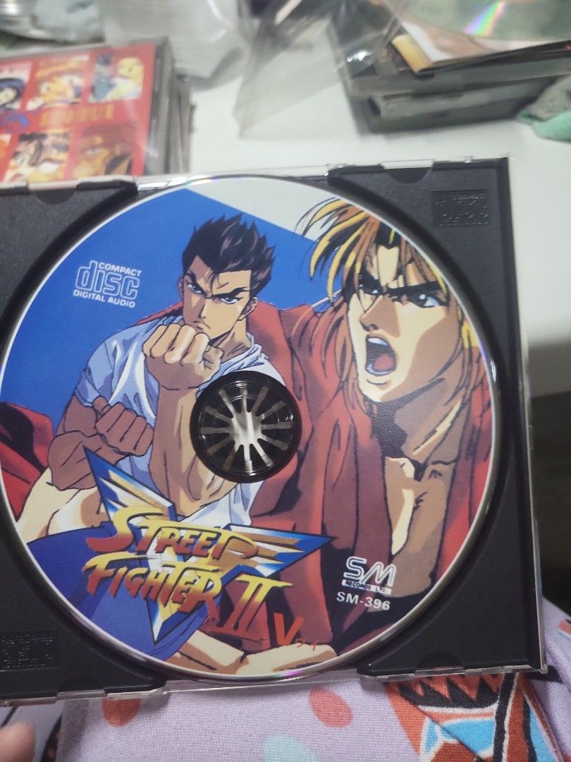 Street Fighter II V CD (Category: CDs & DVDs) located in Caloocan City. Submitted by lynette1977 (Listing ID 1422084147, Image 3). Description: - Original Street Fighter II V CD - Features karaoke versions - Includes tracks: "Fighting Street", "Cry", "Good Luck" - Yellow CD case with character illustrations - Colorful disc design with Street Fighter graphics.
