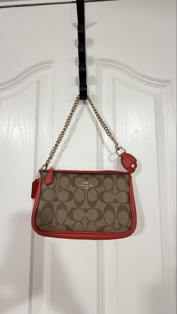 Coach Signature Chain Wristlet OG (Category: Luxury Bags & Wallets) located in Manila. Submitted by loved.sia (Listing ID 1422305583, Image 1). Description: - WITH DUSTBAG, PAPERBAG - Coach wristlet - Signature brown and tan pattern - Red trim - Chain strap - Includes a small red charm - Zipper closure - Coach logo visible - Authentic.