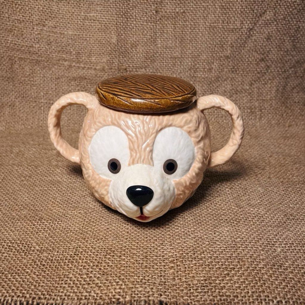 Disney Duffy Bear Ceramic 3D Mug with Cover (Category: Food Organization & Storage) located in Bulacan. Submitted by ceramicscubby (Listing ID 1422374050, Image 1). Description: Size: 2.3 D x 3.75 H in. ❗️ALL PRICES ARE MARKED DOWN❗️ - Adorable Duffy Bear ceramic mug. - Features a detailed bear face design. - Includes a lid with a wooden-like texture. - Has two handles. - Marked "Disney" and "Made in Thailand". - Ideal for collectors and Disney f