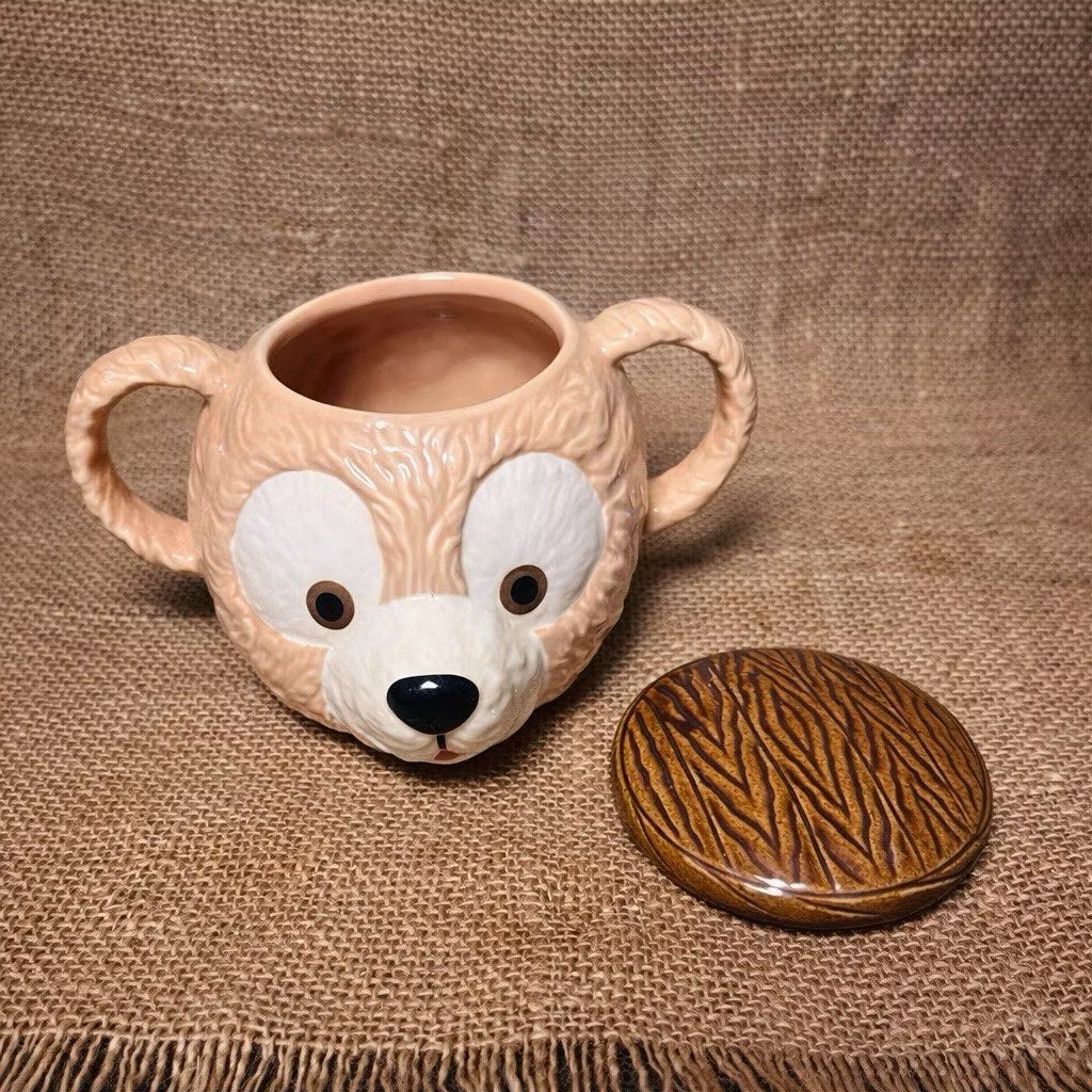 Disney Duffy Bear Ceramic 3D Mug with Cover (Category: Food Organization & Storage) located in Bulacan. Submitted by ceramicscubby (Listing ID 1422374050, Image 2). Description: Size: 2.3 D x 3.75 H in. ❗️ALL PRICES ARE MARKED DOWN❗️ - Adorable Duffy Bear ceramic mug. - Features a detailed bear face design. - Includes a lid with a wooden-like texture. - Has two handles. - Marked "Disney" and "Made in Thailand". - Ideal for collectors and Disney f