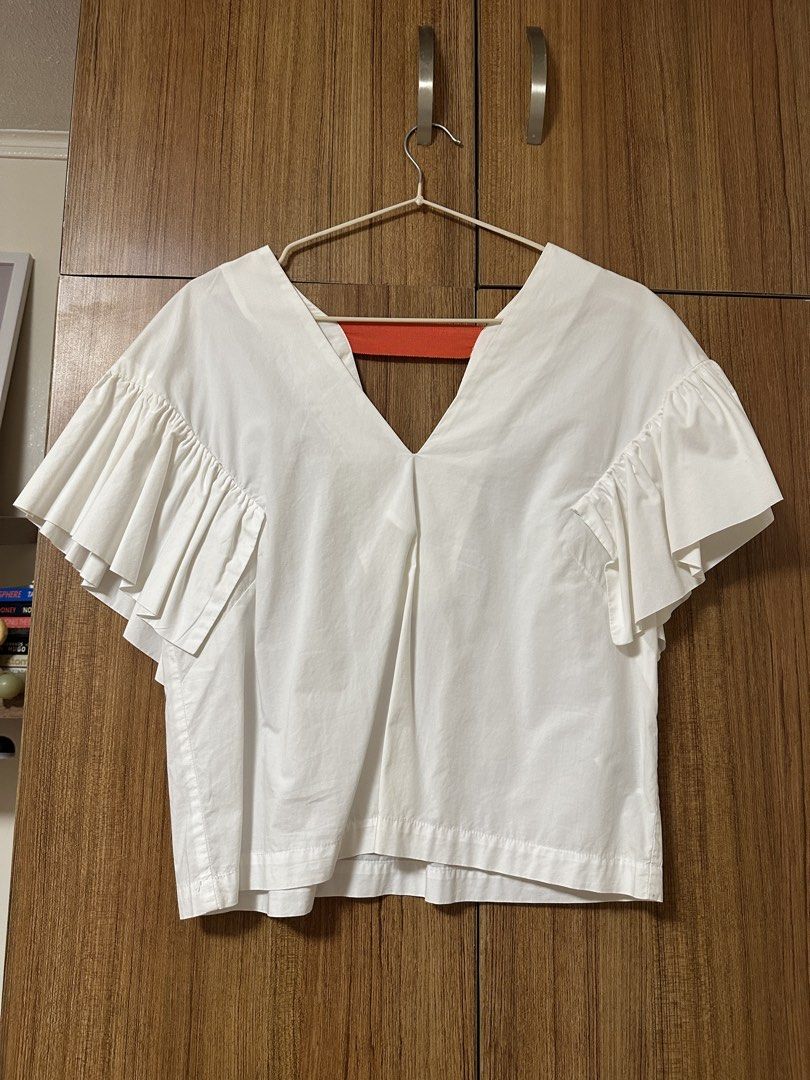 H&M V-neck ruffled wing sleeves blouse (Category: Blouses) located in Quezon City. Submitted by declutters.bianca (Listing ID 1422343334, Image 1). Description: H&M V-neck ruffled wing sleeves blouse white with orange band at the backpack RFS: Decluttering 📍QC/BGC/Makati.