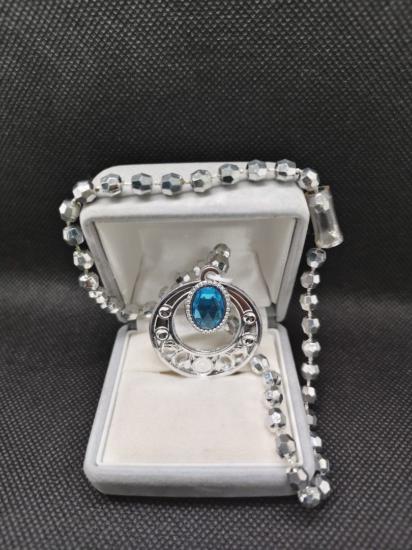 Silver Pendant Necklace with Blue Gem (Category: Necklaces) located in San Mateo. Submitted by joryee (Listing ID 1422305486, Image 3). Description: - Silver necklace with a circular pendant - Intricate detailing on the pendant - Features a vibrant blue gemstone - Beaded chain design - Suitable for various occasions.