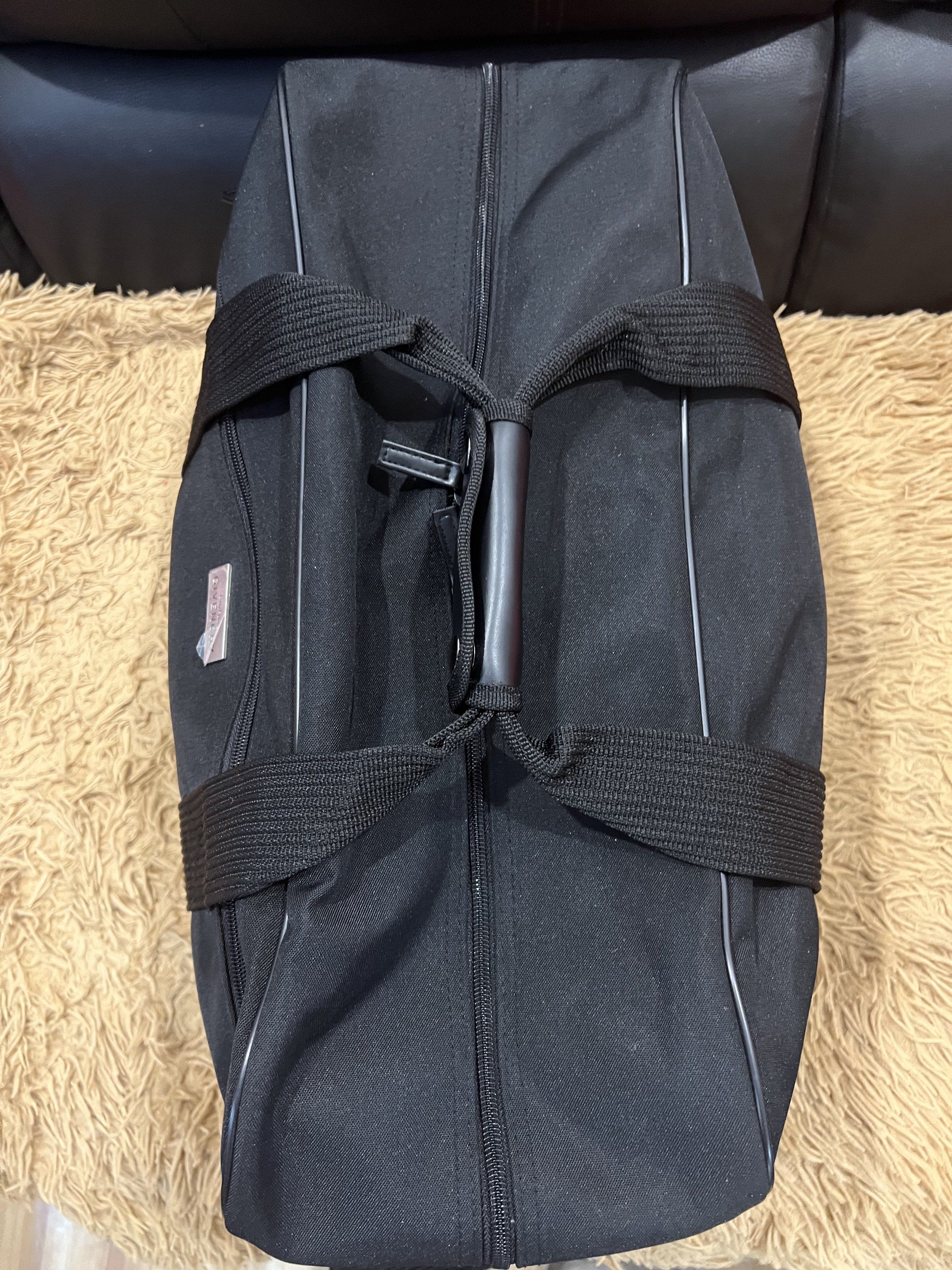 Givenchy Black Duffle Bag (Category: Luxury Bags & Wallets) located in Lipa City. Submitted by thyra06 (Listing ID 1419253554, Image 2). Description: - Authentic Givenchy duffle bag - Classic black color - Includes a detachable shoulder strap and top handles - Features the iconic Givenchy logo - Secure zippered main compartment - Constructed with durable materials.