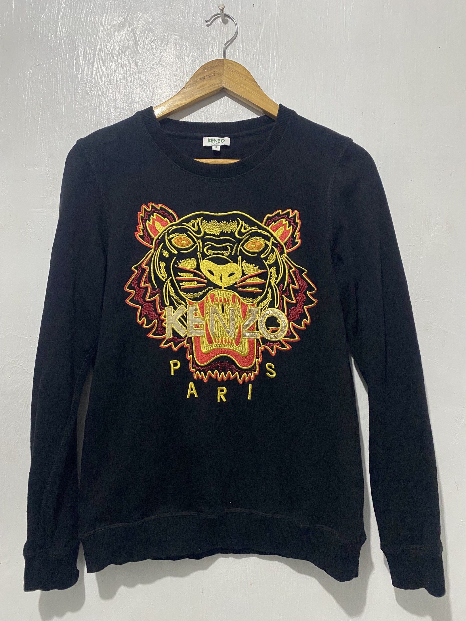 Kenzo Paris Tiger Sweatshirt - Black - Medium (Category: Coats, Jackets and Outerwear) located in Sorsogon. Submitted by ninjathrift (Listing ID 1419384006, Image 1). Description: - Authentic Kenzo Paris sweatshirt - Black color - Features the iconic tiger embroidery - Crew neck design - Size: Medium - Made in Portugal - Long sleeves - Visible care label - Embroidered Kenzo logo on the front -A bit of print issue in some letters of "KENZO".